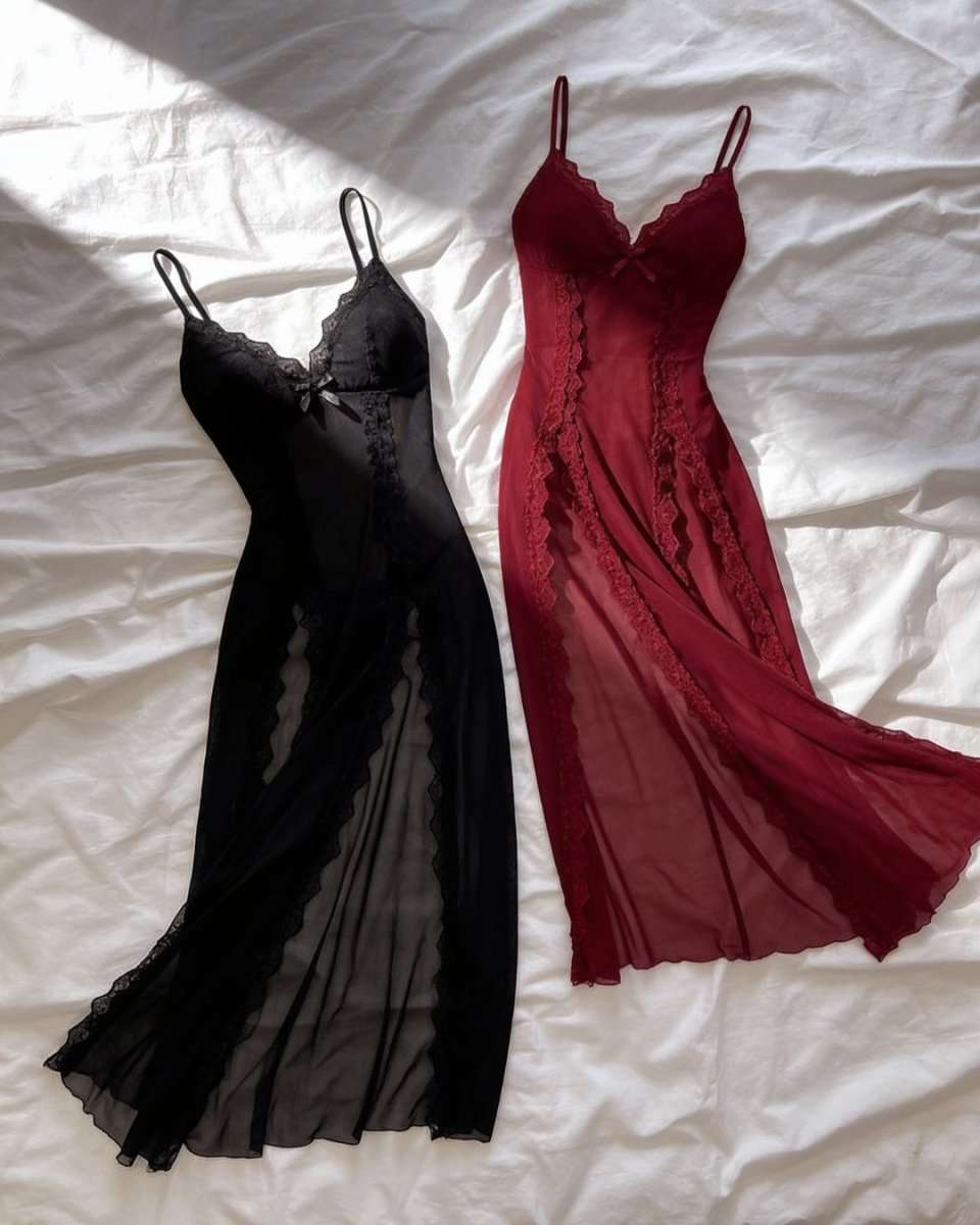 Two sheer lace slip dresses laid flat on white bedding, one in black and one in deep red, both with thin straps and lace trim.