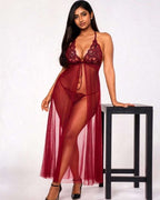 A woman models a sheer burgundy lace babydoll lingerie chemise with matching underwear, standing next to a black stool against a white studio background.